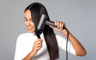 Femme qui se sèche les chevaux à l'aide d'un sèche cheveux.