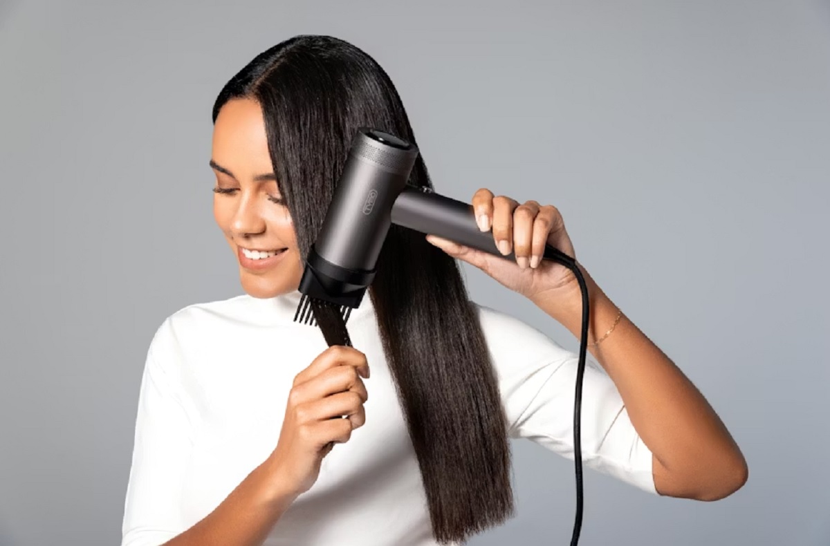 Femme qui se sèche les chevaux à l'aide d'un sèche cheveux.